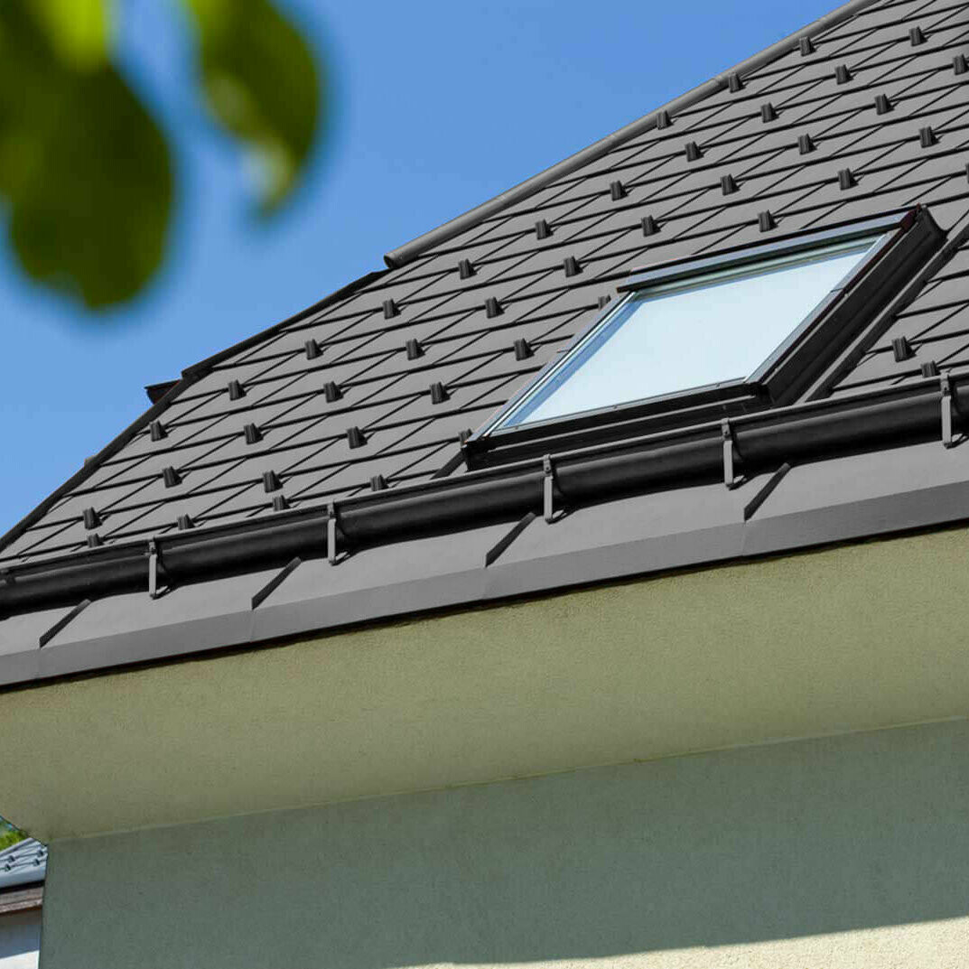 Referenzbild einer PREFA Saumrinne mit Dachfenster mit schwarzem Dach.