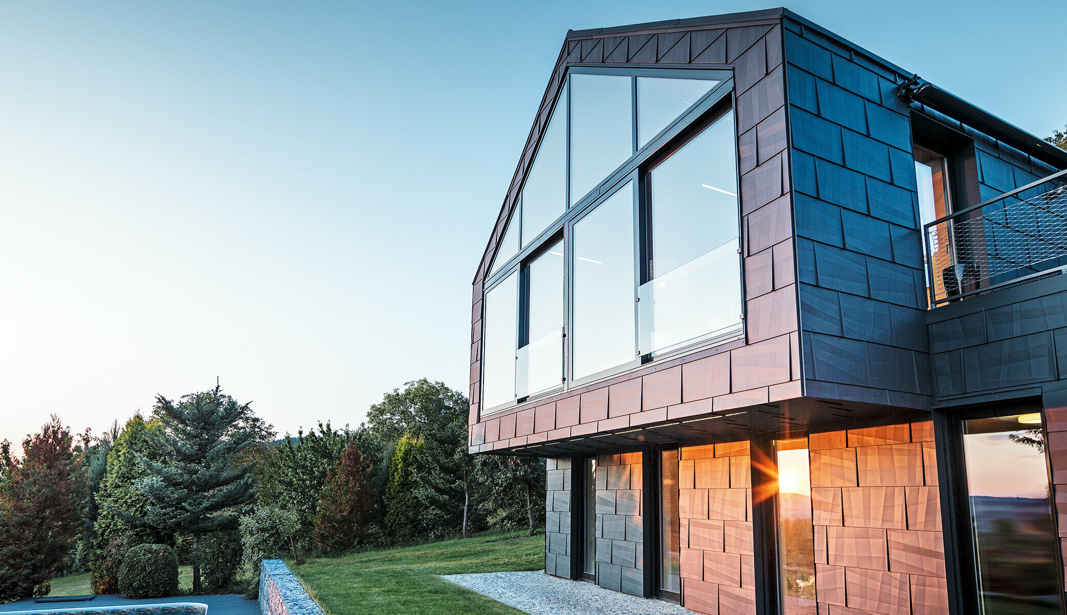 Modern detached house without eaves; with large windows and FX.12 façade in anthracite, photographed at sunset.