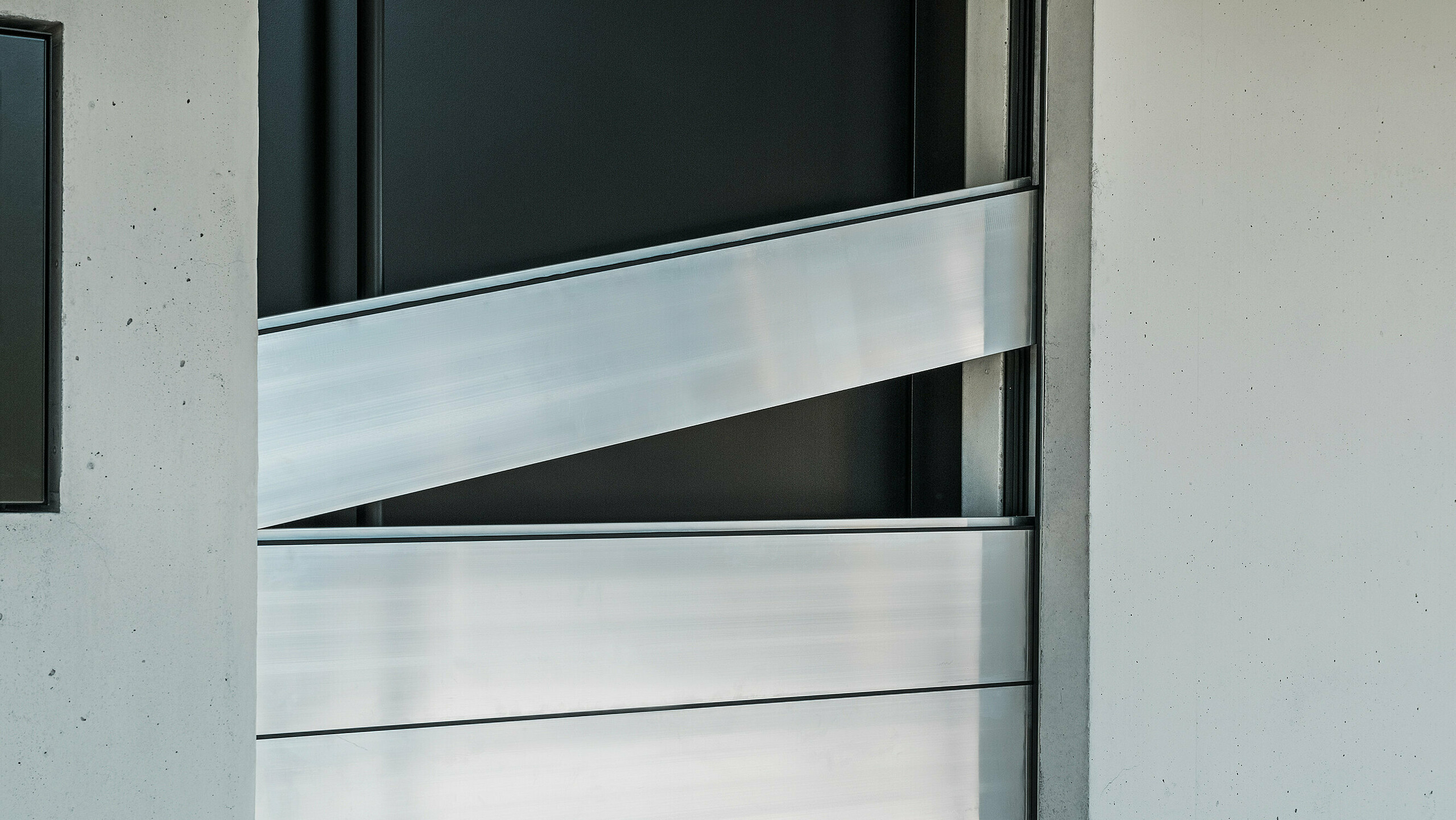 Detailansicht der Verbindungselemente des PREFA Hochwasserschutzsystems. Die innovative Technik sorgt für eine sichere Abdichtung der Haustür und schützt effektiv vor Hochwasser. Die Dammbalken werden schräg eingeschoben, wie am oberen Element deutlich zu erkennen ist.