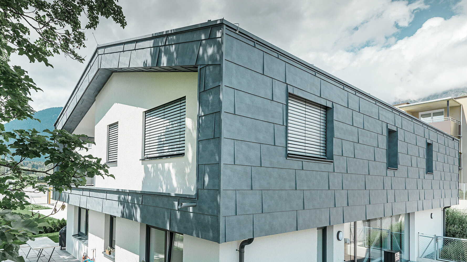 Modern detached house without eaves; the upper floor was  clad with PREFA FX.12 façade panels in stone grey, the rest of the façade was plastered white.