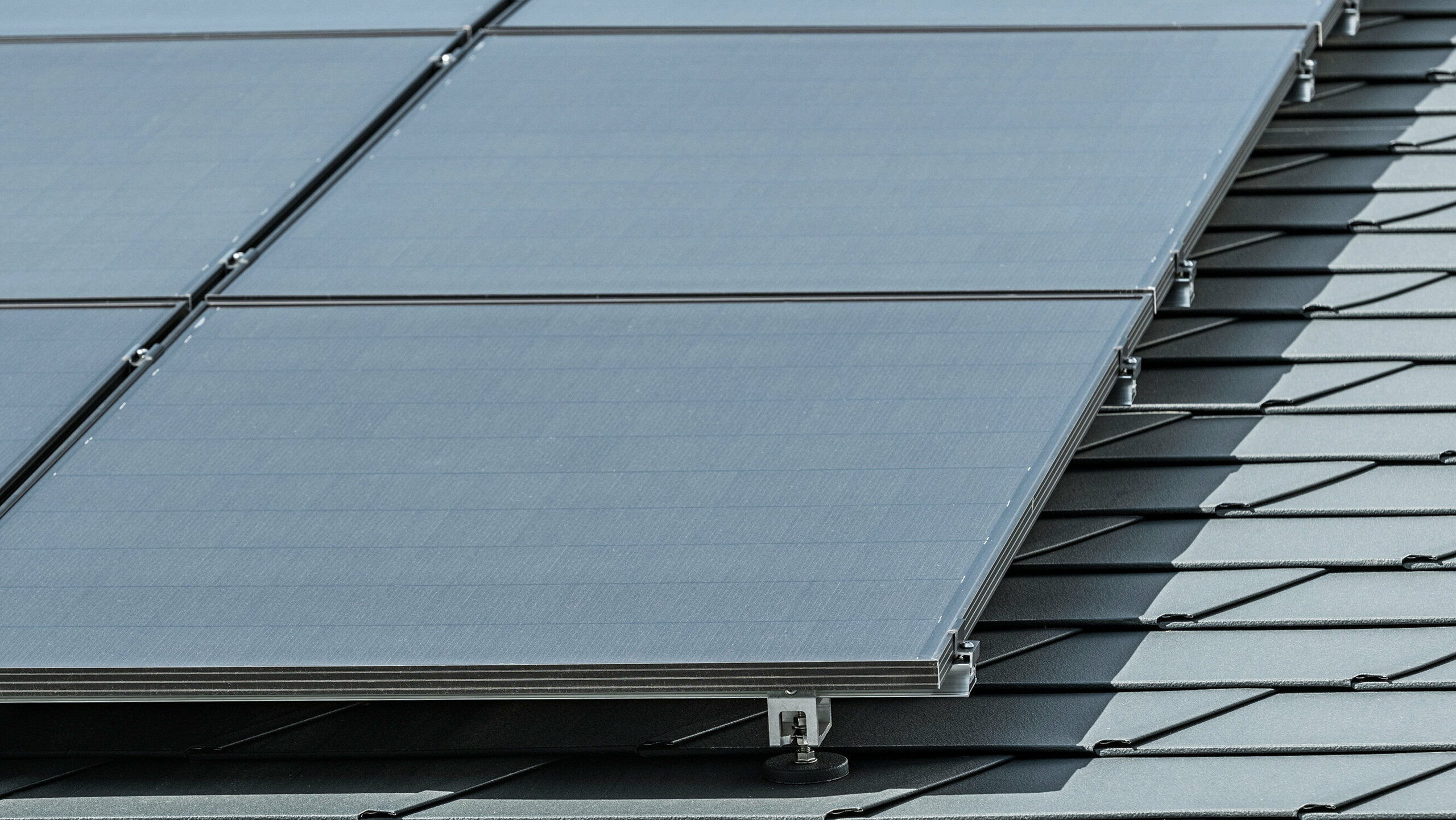 Close-up of a photovoltaic system mounted on PREFA roof shingles DS.19 in P.10 anthracite with PREFA Solar bracket Vario