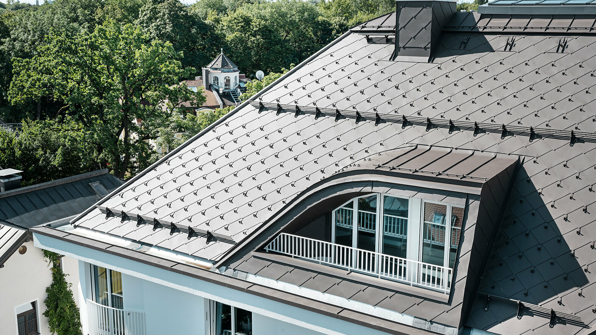 Apartment building with PREFA rhomboid roof tiles 44 × 44 in brown with snow guards and snow rakes