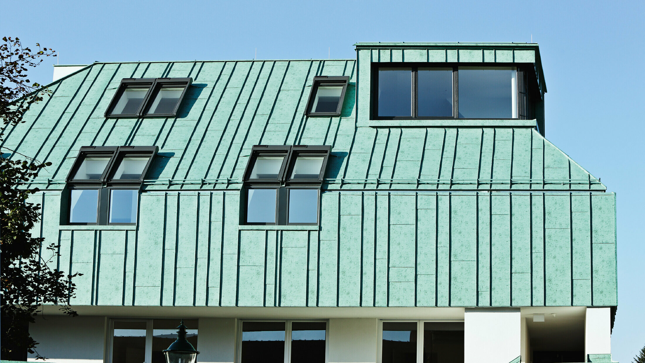 Roof and façade design with PREFALZ standing seam in patina green from PREFA in different panel widths.