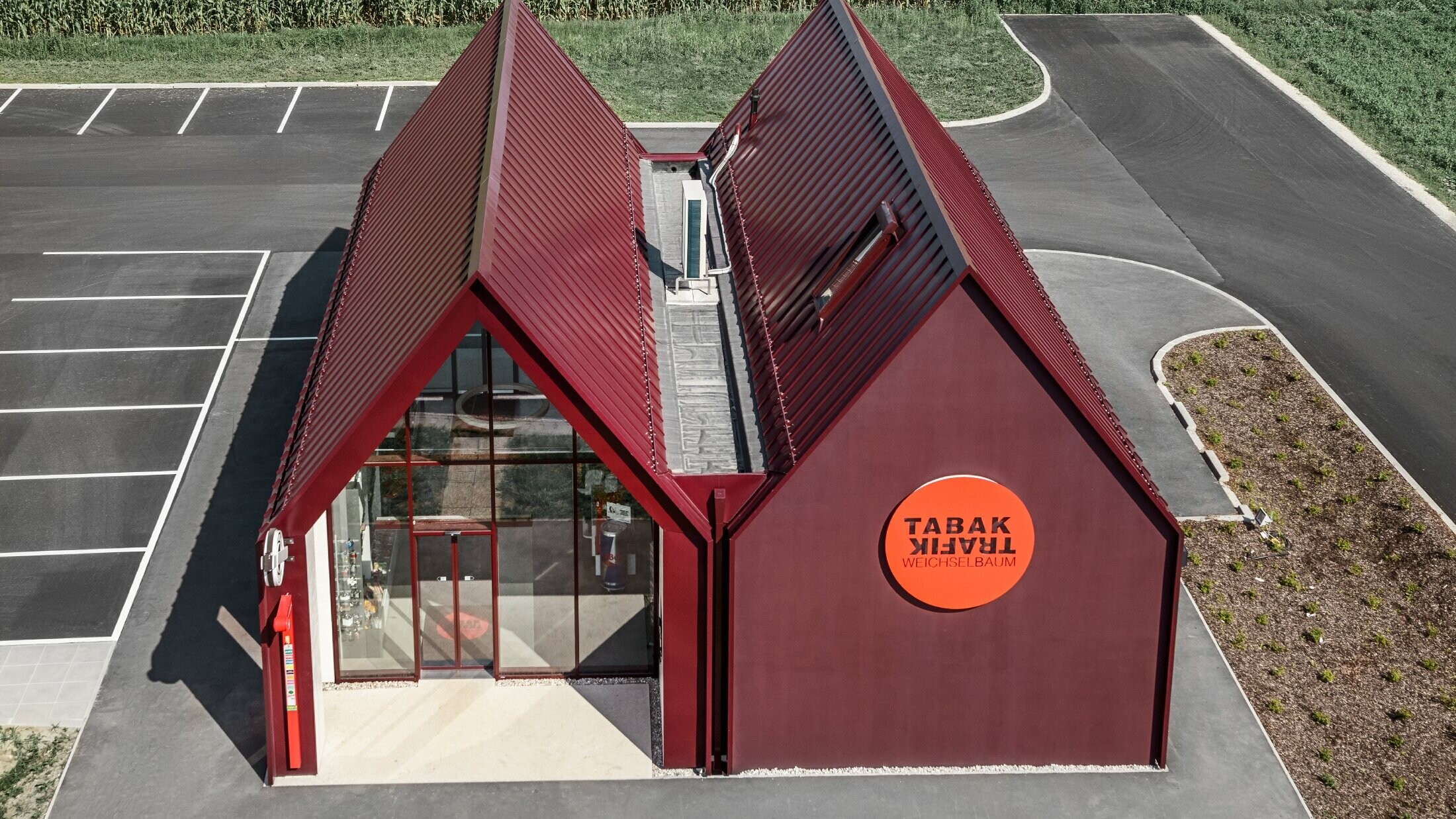 Modern tobacconist with gable roof (without overhanging eaves) and an aluminium coating by PREFA with standing and single lock standing seam in the special colour of black red